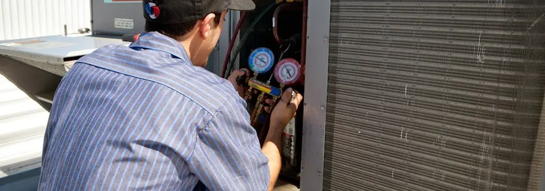HVAC technician servicing a condenser unit in Dunlap
